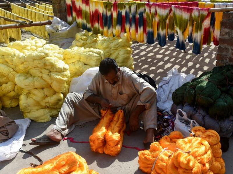 A Pakistani worker collects fabric threads after dyeing at a factory in Lahore on February 11, 2019. 
ARIF ALI / AFP