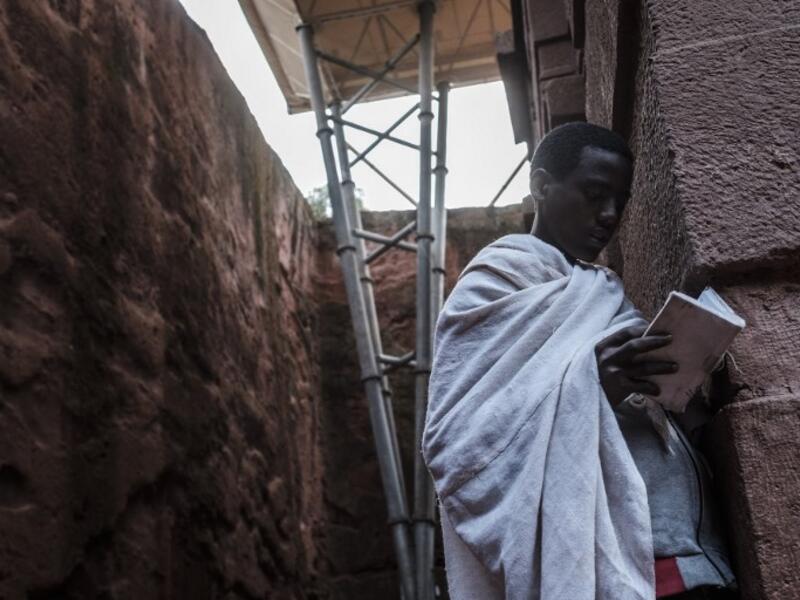An Ethiopian Orthodox devotee reads a bible near the pillar of a shelter protecting from erosion the rock-hewn structure of the church of Saint Emmanuel in Lalibela, Ethiopia
EDUARDO SOTERAS / AFP