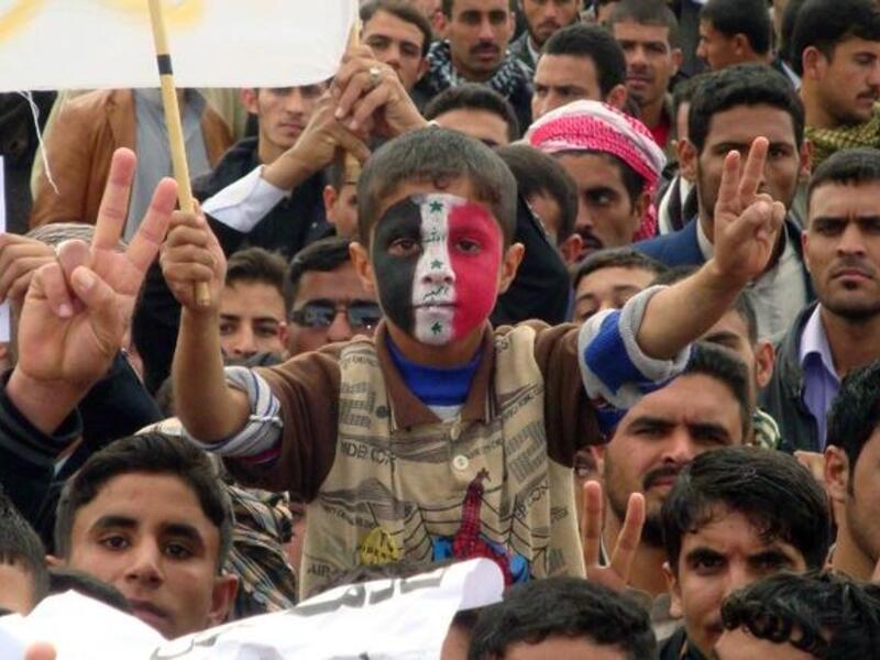 An Iraqi boy, whose face is made up with the national flag, flashes the sign of victory during a rally following the Friday's prayers to call for the government's fall. (AFP PHOTO/MARWAN IBRAHIM)