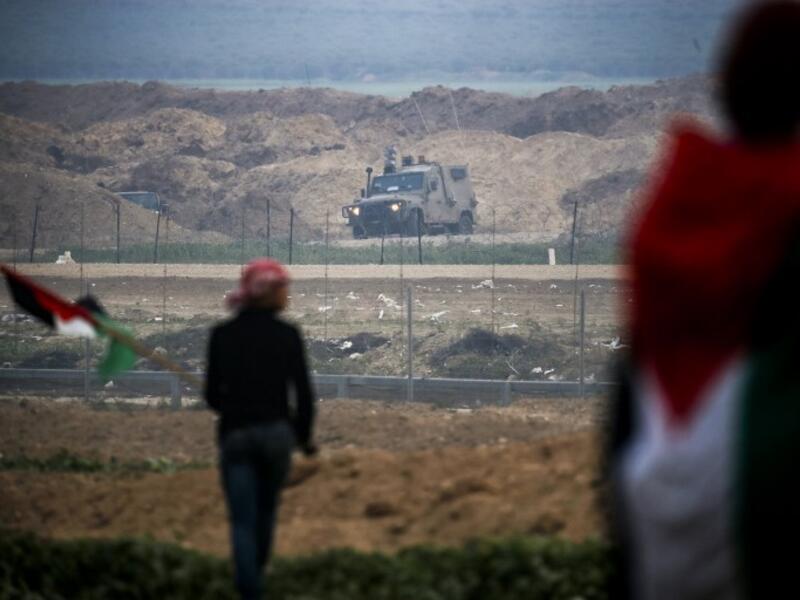 Gaza Strip east of Gaza City shows Palestinians protesting with Palestinian flags by the barbed-wire fence along the border with Israel, with an Israeli army vehicle seen across on the other side. (Said KHATIB / AFP)