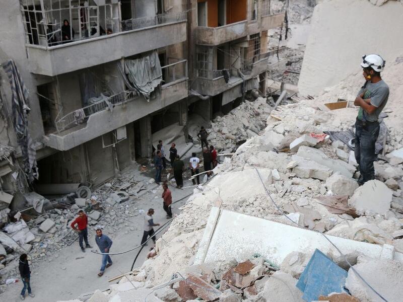 A Syrian civil defence volunteer, known as the White Helmets, stands on the rubble of destroyed buildings during a rescue operation following a government forces air strike on the rebel-held neighbourhood of Bustan al-Basha in Aleppo. (AFP/Thaer Mohammed)