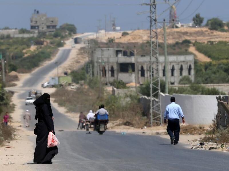 A Palestinian woman waits to be picked up on a road between the coast and the former Jewish settlement of Netzarim, south of Gaza City. (AFP/File) 