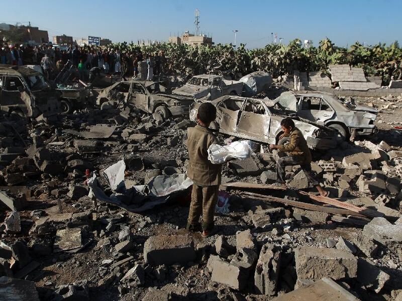 Yemenis stand at the site of a Saudi air strike against Huthi rebels near Sanaa Airport on March 26, 2015.  (AFP/Mohammed Huwais)