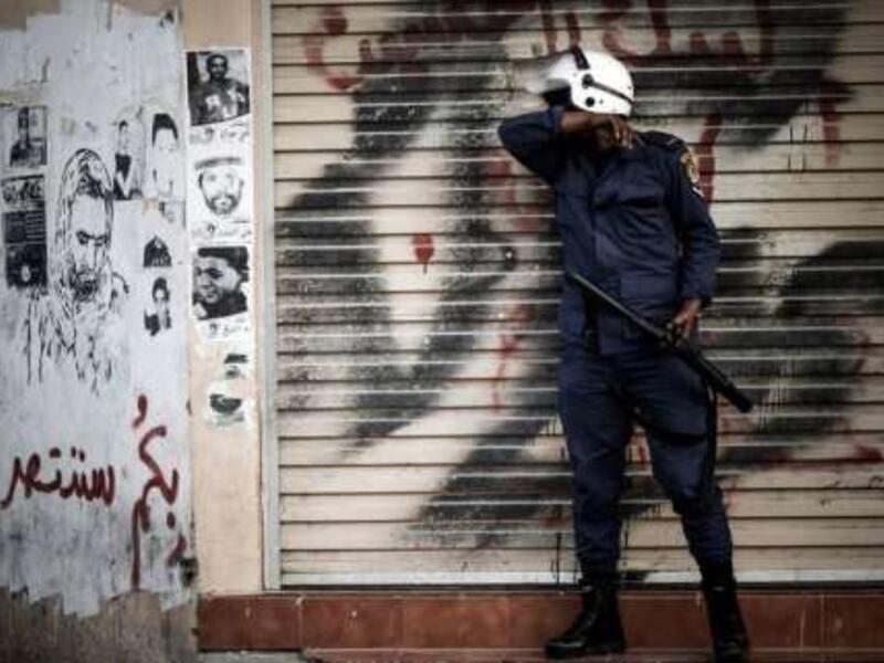 A Bahraini policeman stands in front of graffiti in 2013. (AFP/File)