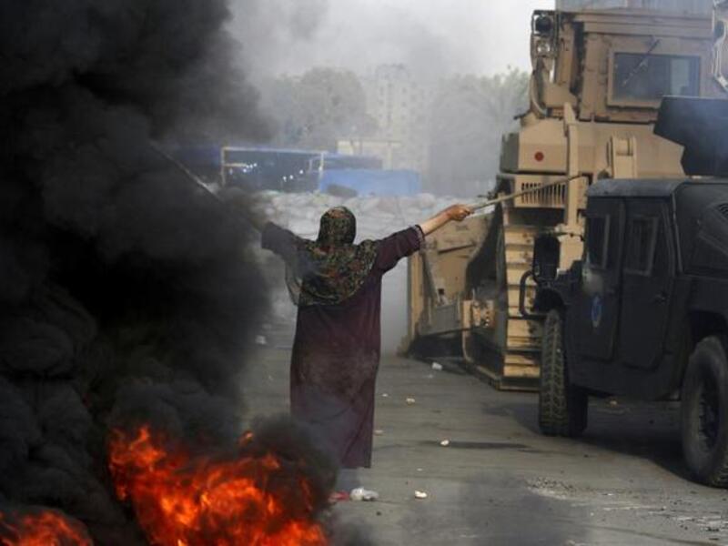 EGYPT, Cairo : An Egyptian woman tries to stop a military bulldozer from going forward during clashes that broke out as Egyptian security forces moved in to disperse supporters of Egypt's deposed president Mohamed Morsi in a huge protest camp near Rabaa al-Adawiya mosque in eastern Cairo on August 14, 2013. AFP PHOTO /MOHAMMED ABDEL MONEIM