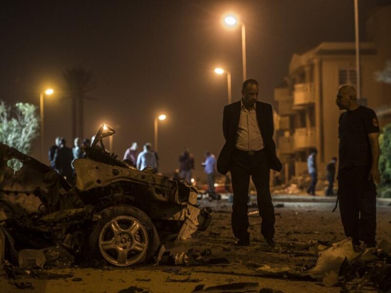 Egyptian officials inspect the wreckage of a car bomb that exploded in a Cairo suburb after Egypt's deputy prosecutor general drove by late on September 29, 2016, wounding a passerby. (AFP/Khaled Desouki)