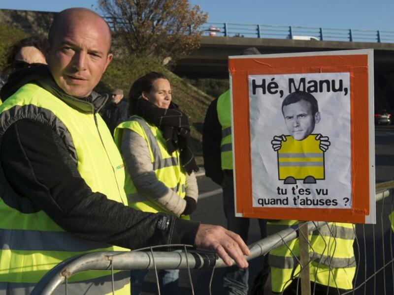 Protestors stand near a picture representing French President Emmanuel Macron while they slow down traffic on a road in Saint-Herblain, near Nantes, western France, on November 18, 2018.
SEBASTIEN SALOM GOMIS / AFP