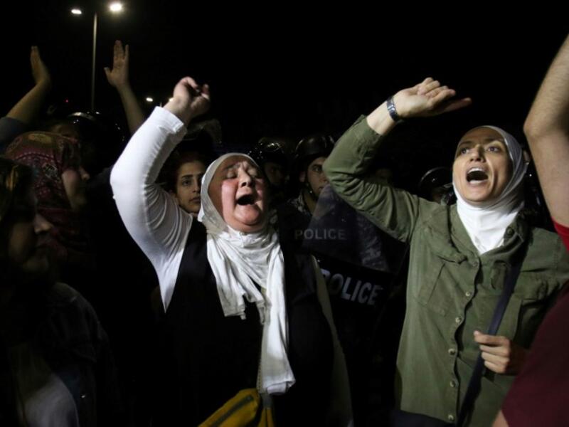Protesters raise their fists near riot police officers during a demonstration outside the prime minister's office in the capital Amman late on June 3, 2018. 
Khalil MAZRAAWI / AFP