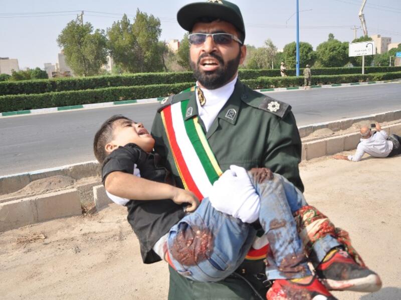 A member of Iran's Revolutionary Guards Corps (IRGC) carrying an injured child at the scene of an attack on a military parade that was marking the anniversary of the outbreak of its devastating 1980-1988 war with Saddam Hussein's Iraq. (Behrad GHASEMI / ISNA / AFP)