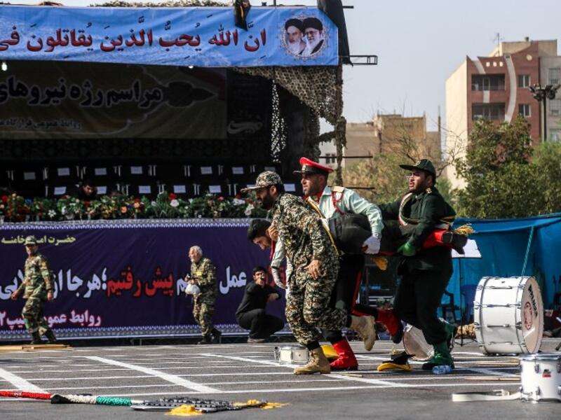 This picture taken on September 22, 2018 in the southwestern Iranian city of Ahvaz shows Iranian soldiers carrying away an injured comrade at the scene of an attack on a military parade that was marking the anniversary of the outbreak of its devastating 1980-1988 war with Saddam Hussein's Iraq. (MORTEZA JABERIAN / ISNA / AFP)