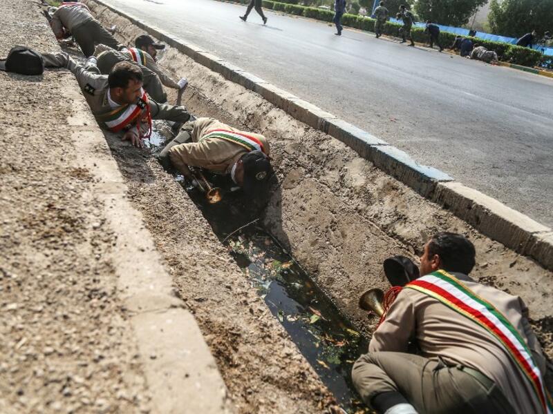This picture taken on September 22, 2018 in the southwestern Iranian city of Ahvaz shows Iranian soldiers taking cover in a rain gutter off a street at the scene of an attack on a military parade that was marking the anniversary of the outbreak of its devastating 1980-1988 war with Saddam Hussein's Iraq.(MORTEZA JABERIAN / ISNA / AFP)