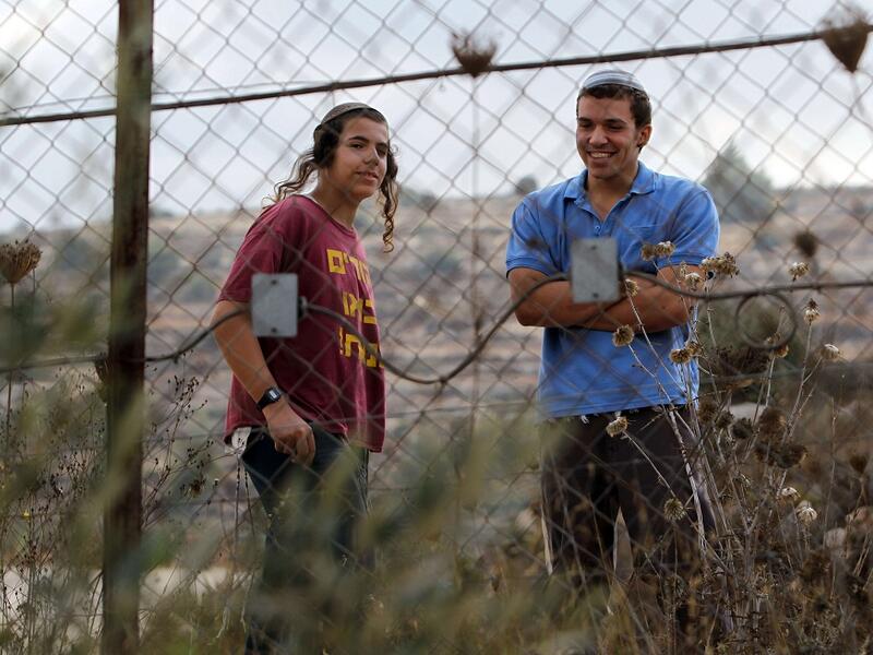 Two Israeli settlers watch Palestinian villagers following a price-tag attack in the West Bank. (AFP/File)