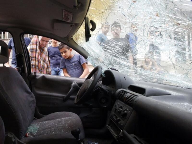Palestinians look at a damaged car belonging to a Palestinian man who was killed by Israeli security forces after he attempted to ram his vehicle into Israeli border guards early in the morning in the Shufat refugee camp, in east Jerusalem, on September 5, 2016. (AFP/Hazem Bader)