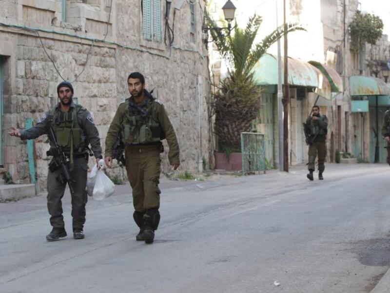 Israeli soldiers walk in the West Bank city of Hebron, where children as young as 13 were detained this morning. (AFP/File)