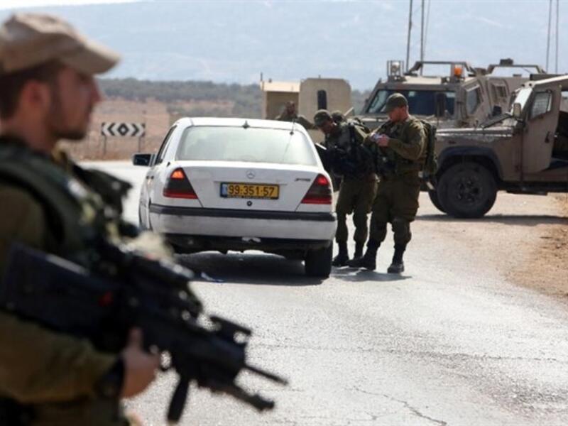 Israeli soldiers examine a car at a checkpoint east of Nablus. (AFP/File)