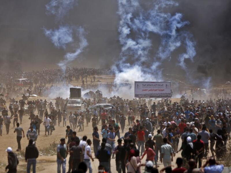 Palestinians run for cover from tear gas during clashes with Israeli security forces near the border between Israel and the Gaza Strip, east of Jabalia/AFP