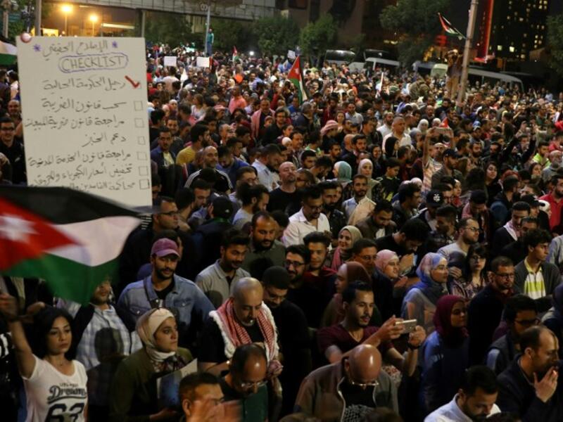 Demonstrators wave flags and hold signs during a protest in Amman, Jordan, near the prime minister's office, June 4, 2018. Protestors have demonstrated for the fifth night against the new proposed income tax draft law and other anti-austerity measures. Khalil Mazeraawi/ AFP) 
