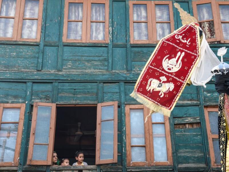 Kashmiri muslim family watches from a window of a residential house as Kashmiri Shiite Muslim mourners flagellate themselves during a religious procession.Tauseef MUSTAFA / AFP