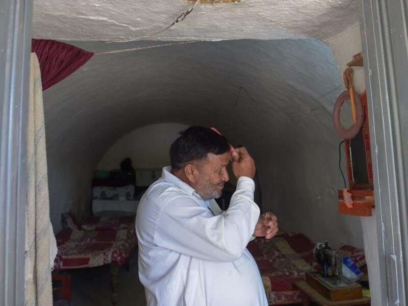Pakistani villager Haji Abdul Rasheed combs his hair at the entrance to his cave room in Nikko village. 
AAMIR QURESHI / AFP