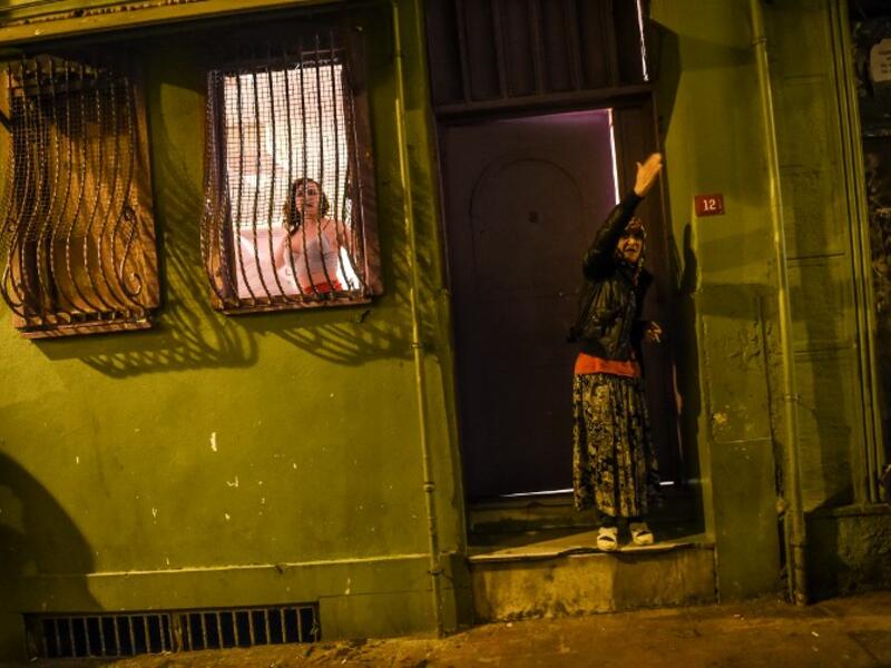 A transgender looks out of a window and a woman reacts as women's rights activists march through Taksim Square to protest against gender violence in Istanbul, on November 25, 2018, on the International Day for the Elimination of Violence against Women. 
BULENT KILIC / AFP