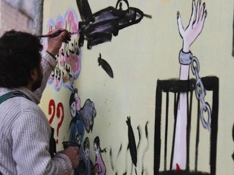Syrian artist Aziz al-Asmar works on a mural depicting the war ahead of the start of the Astana peace talks. (AFP/ File Photo)