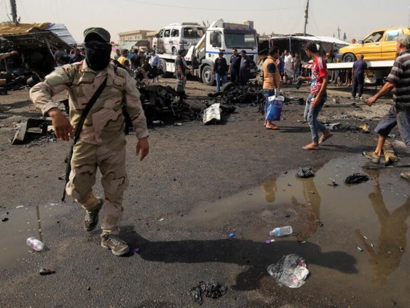 Iraqi soldiers and civilians check the damage after a suicide bomber detonated an explosives-rigged vehicle in northern Baghdad's Sadr City, May 17, 2016. (AFP/Ahmad al Rubaye)