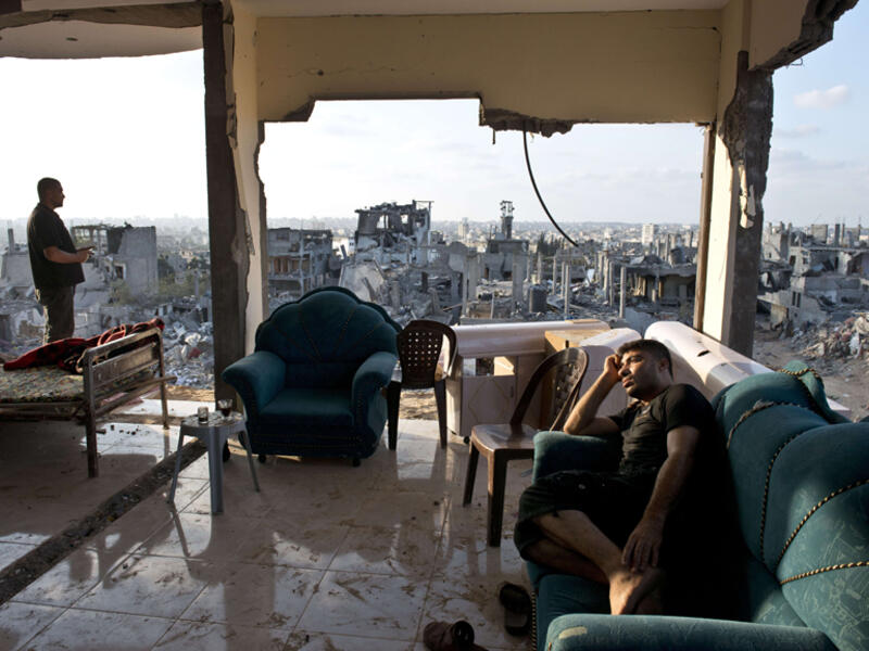 Two young men sit among the aftermath of brutal Israeli offensive on Gaza. (AFP/Roberto Schmidt)
