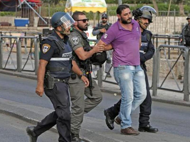 Israeli policemen detain a Palestinian, at the site where two Israeli police officers were stabbed. (AFP/File)