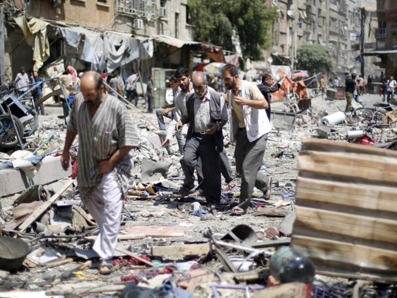 Syrians walk amid the rubble following air strikes by Syrian government forces on a marketplace. (AFP/File)