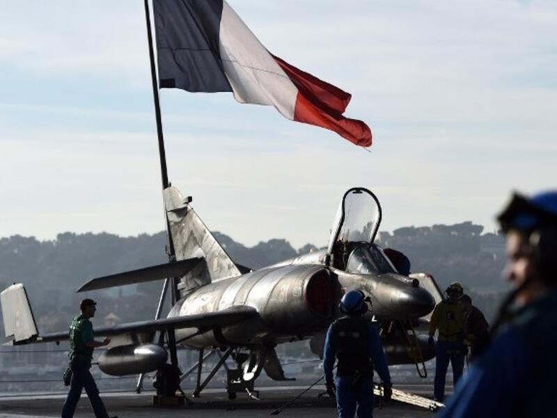 A French flag flies above French naval technicians working on the flight deck of the aircraft (AFP)