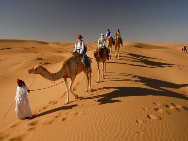Tourists take a camel ride to visit the Bedouin village at Wahiba Sands. (Oman Tourism Ministry)