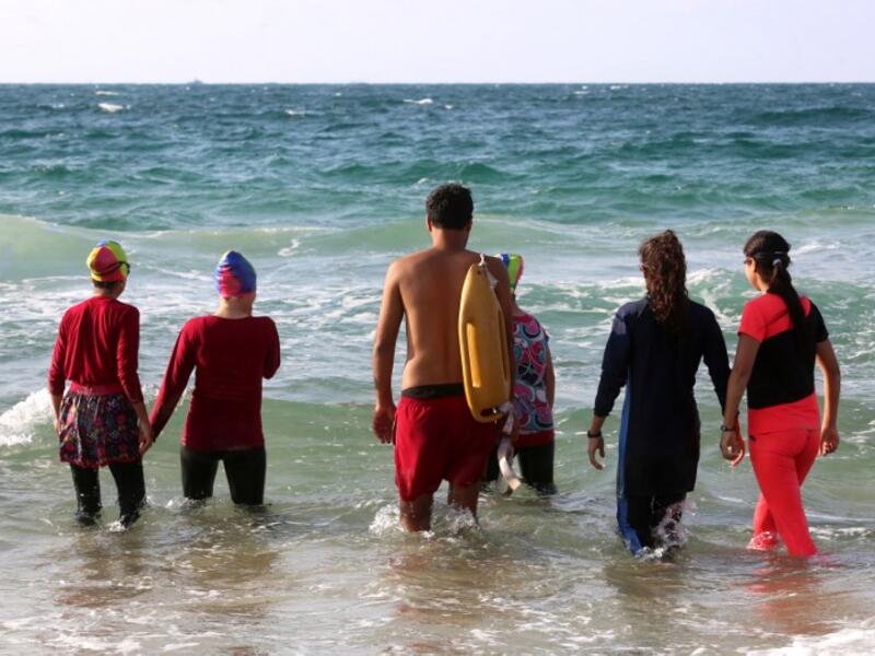 Young Palestinian members of a swimming club, walk into the sea to begin a training session in Beit Lahia. (SAID KHATIB / AFP)