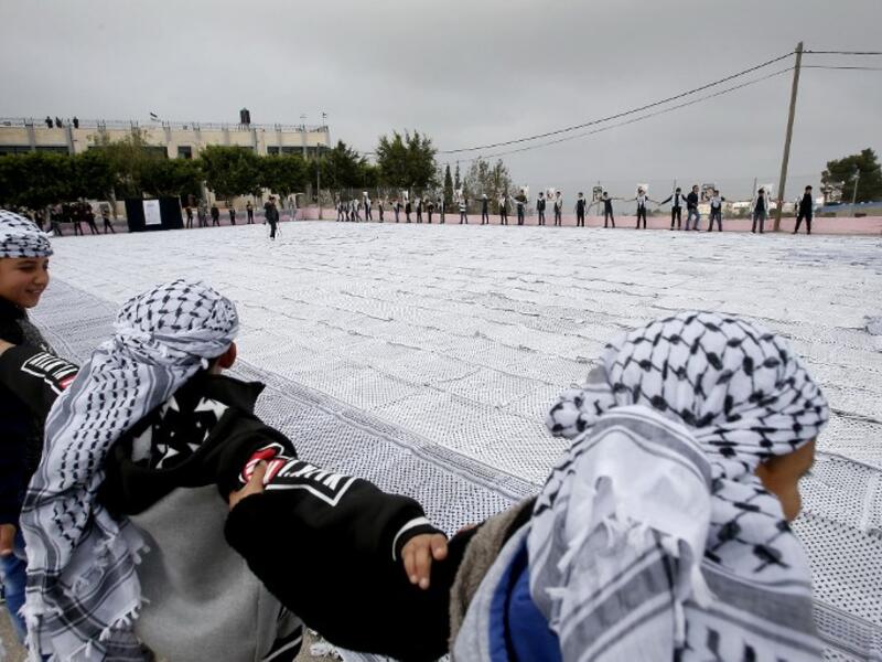 Palestinian students of the Southern Education Direction surround the largest Keffiyeh. (HAZEM BADER / AFP)