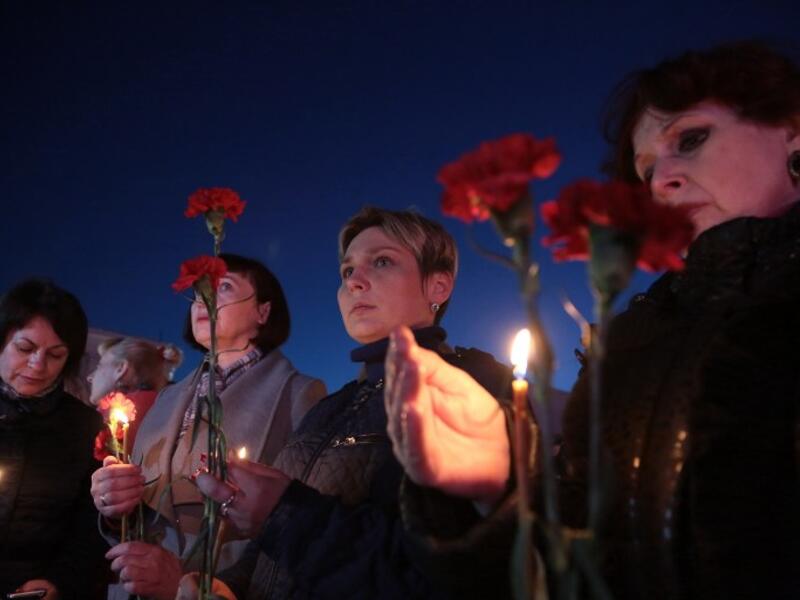Women hold flowers and lit candles as they take part in a gathering in memory of victims of the blast in the Saint Petersburg metro in Simferopol, Crimea, on April 3, 2017. (AFP/Max Vetrov)