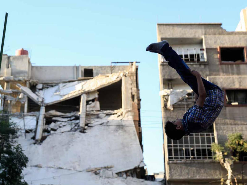 A boy head over heals in Douma, September 2016. The rebel-held city has been under blockage by Syrian government forces since 2013, causing shortages in food and medical supplies. 
