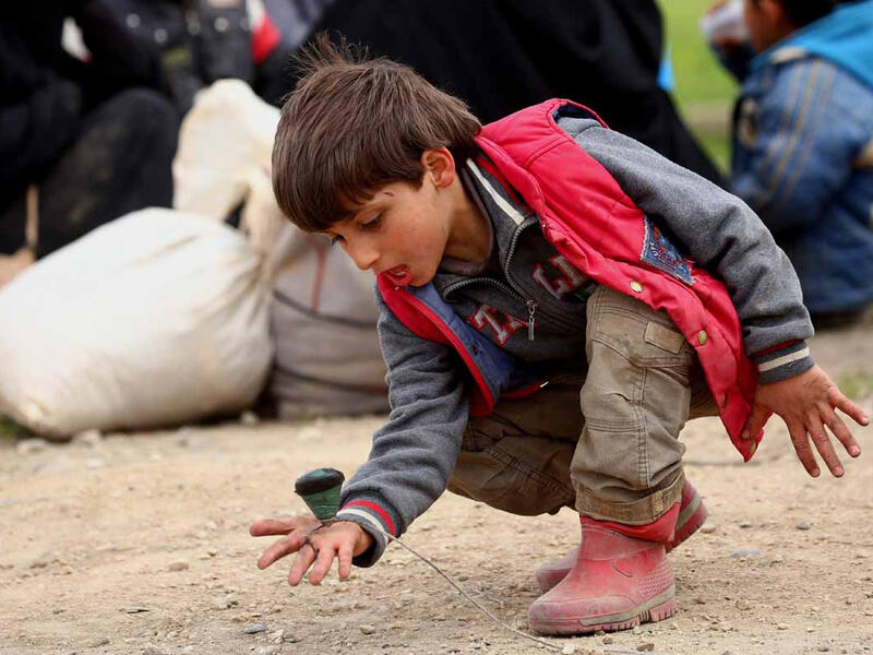 A displaced Syrian boy, who fled Daesh stronghold Raqa, plays with a spinning top at a temporary camp in Syria. Photographer Delil Suleiman: “Sometimes I witness things that give me hope. I saw a truck that had just come in from Raqa. Dust covered the faces of all those on board. And as soon as the kids got off, two of them started playing.”