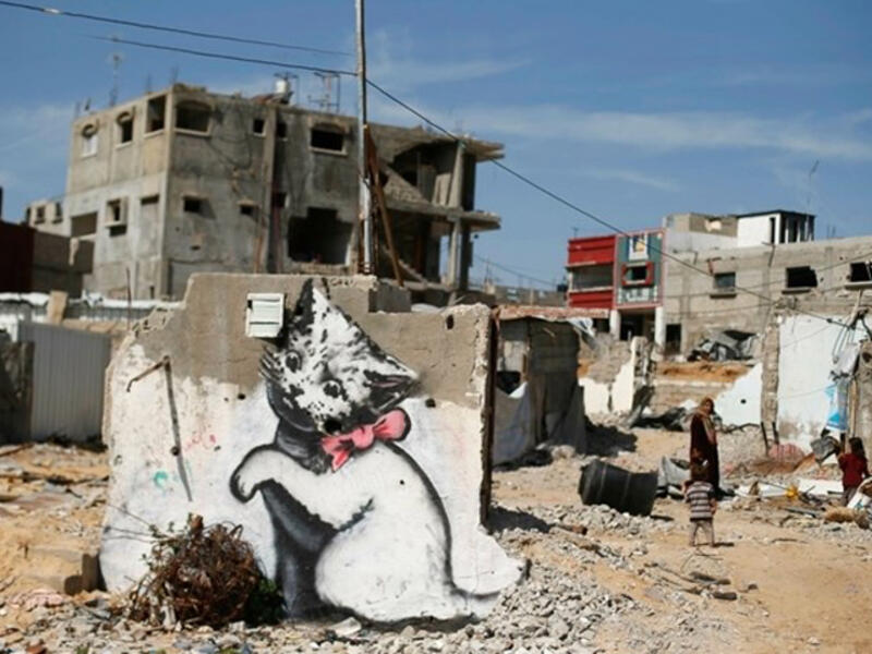 Banksy’s cute kitty plays with a ball of tangled steel (Gazan “yarn”), a jarring contrast to the destruction around him. Says the artist on his website, "A local man came up and said 'what does this mean?' I explained I wanted to highlight the Gaza destruction by posting photos, but on the internet people only look at pictures of kittens."