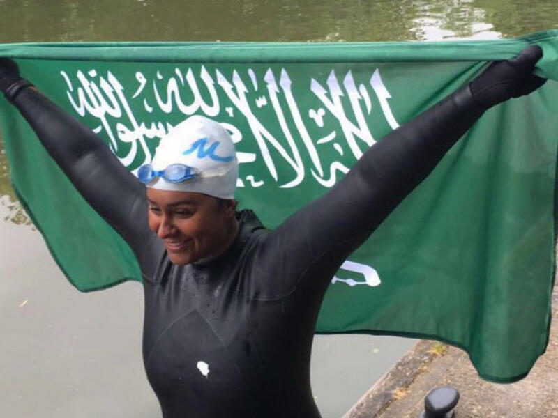 Mariam Binladen triumphantly holds the Saudi flag after completing the 101-mile swim of the Thames. (Twitter)