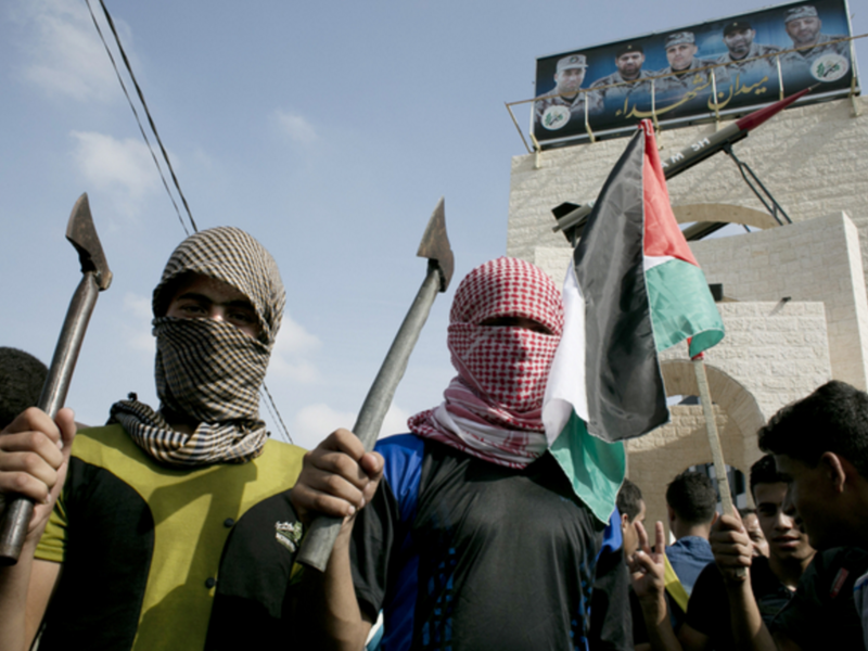 Palestinian students in checkered keffiyehs holding axes. (photo: AFP) 