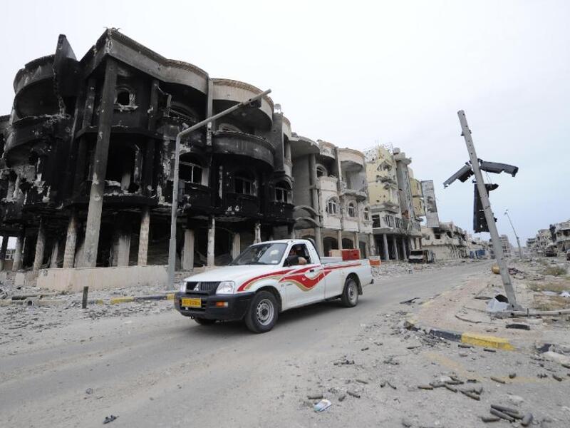 A truck parked in front of a bombed building in Sirte, Libya. (AFP/File)