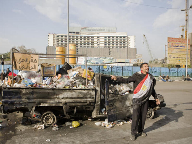 A burnt car filled with garbage sports a sign reading, "National Party Headquarters".