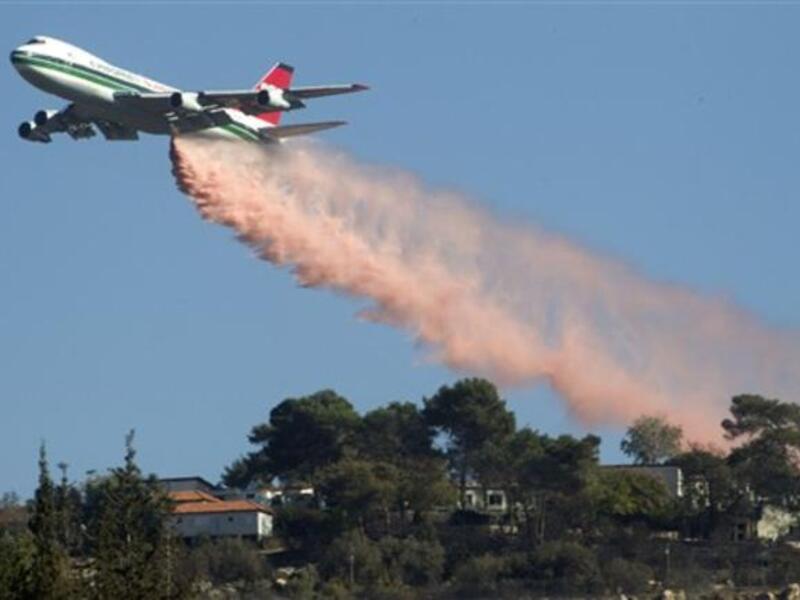 US Evergreen 747 supertanker sprays over an area in Ein Hod in the Carmel Forest in the outskirts of Haifa, as dozens of firefighting planes from around the world battled the blaze, which has killed 41 people so far.