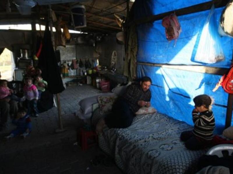 Members of a displaced Palestinian family sit outside their tent.
