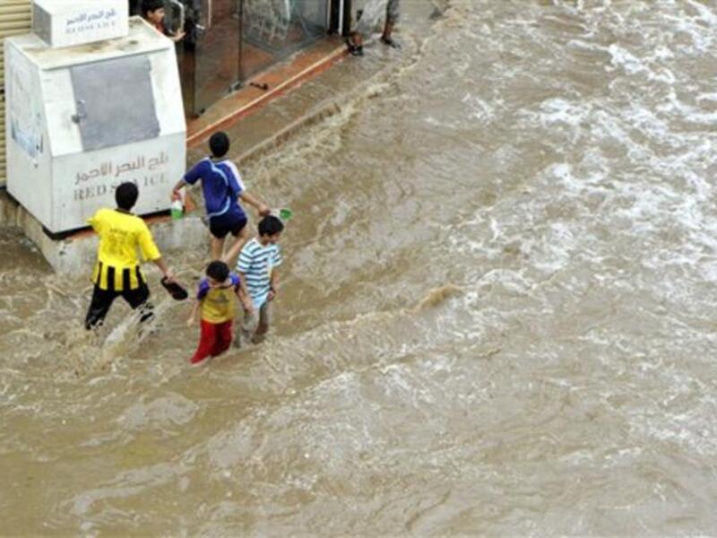 Saudi children walk through a flooded street following heavy rain.