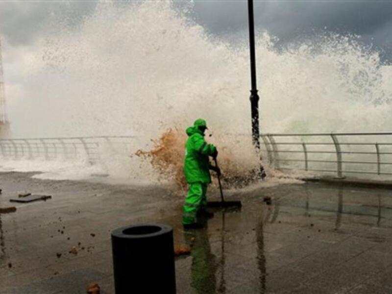 A municipality worker clears the mud as high waves rip off paving stones on Beirut's Mediterranean promenade.