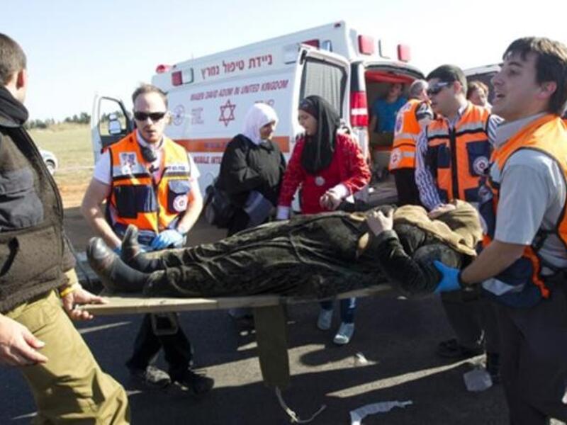 A wounded Arab Israeli woman is evacuated from a burning train coach by paramedics near Kibbutz Shfaim.