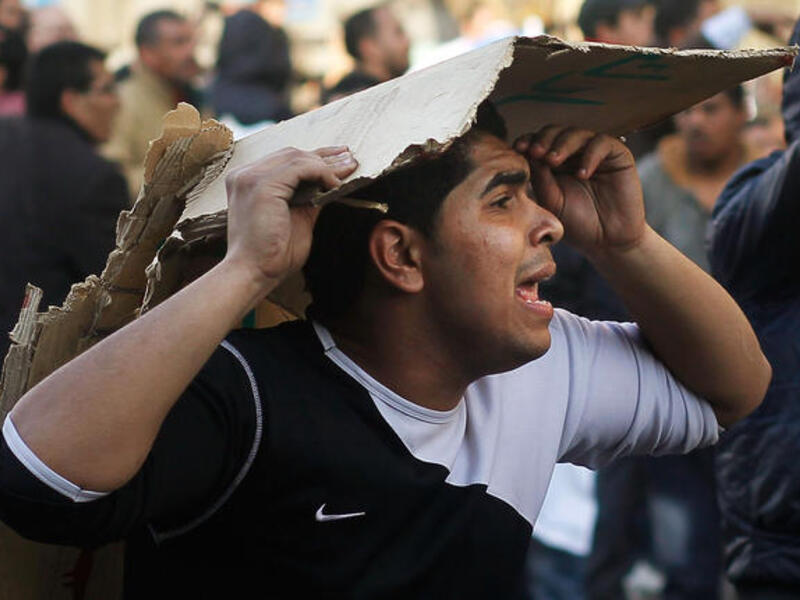 An opponent of embattled Egyptian president Hosni Mubarak tries to protect his head while calling for reinforcements during a clash between pro- and anti-Mubarak protesters.