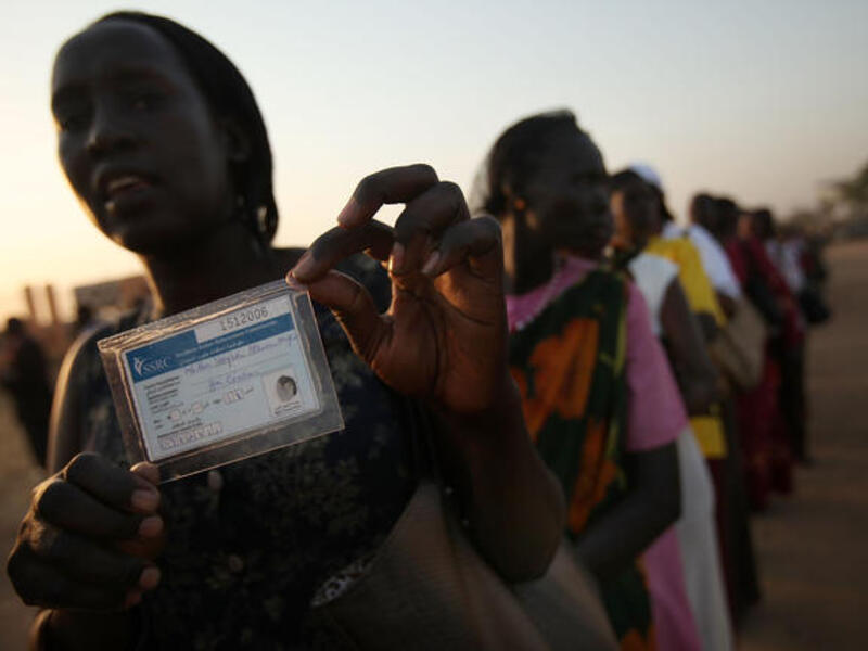 A woman displays her voting card while in line to vote.