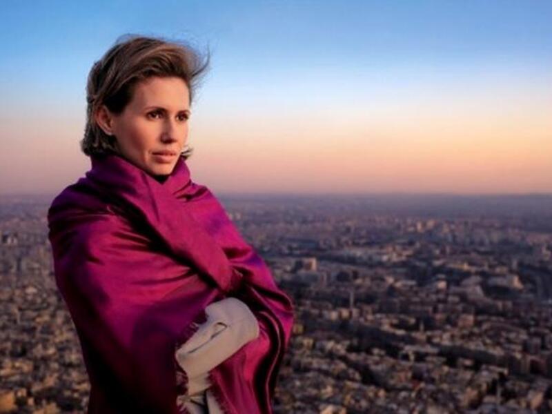 أسماء الأسد وتظهر مدينة دمشق في خلفية الصورة
