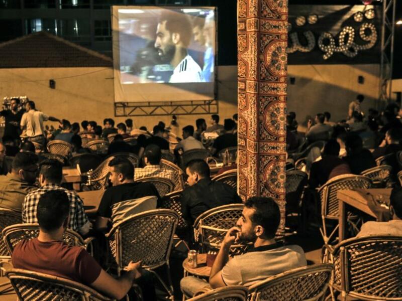 Palestinians watch on a big screen the Russia 2018 World Cup Group A football match between Russia and Egypt at at a coffeehouse in Gaza City.